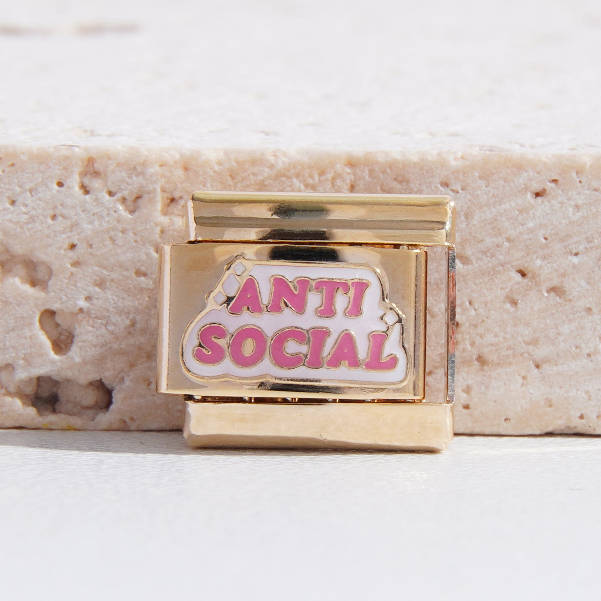 Pink Anti Social lettering on a gold-tone rectangular charm link