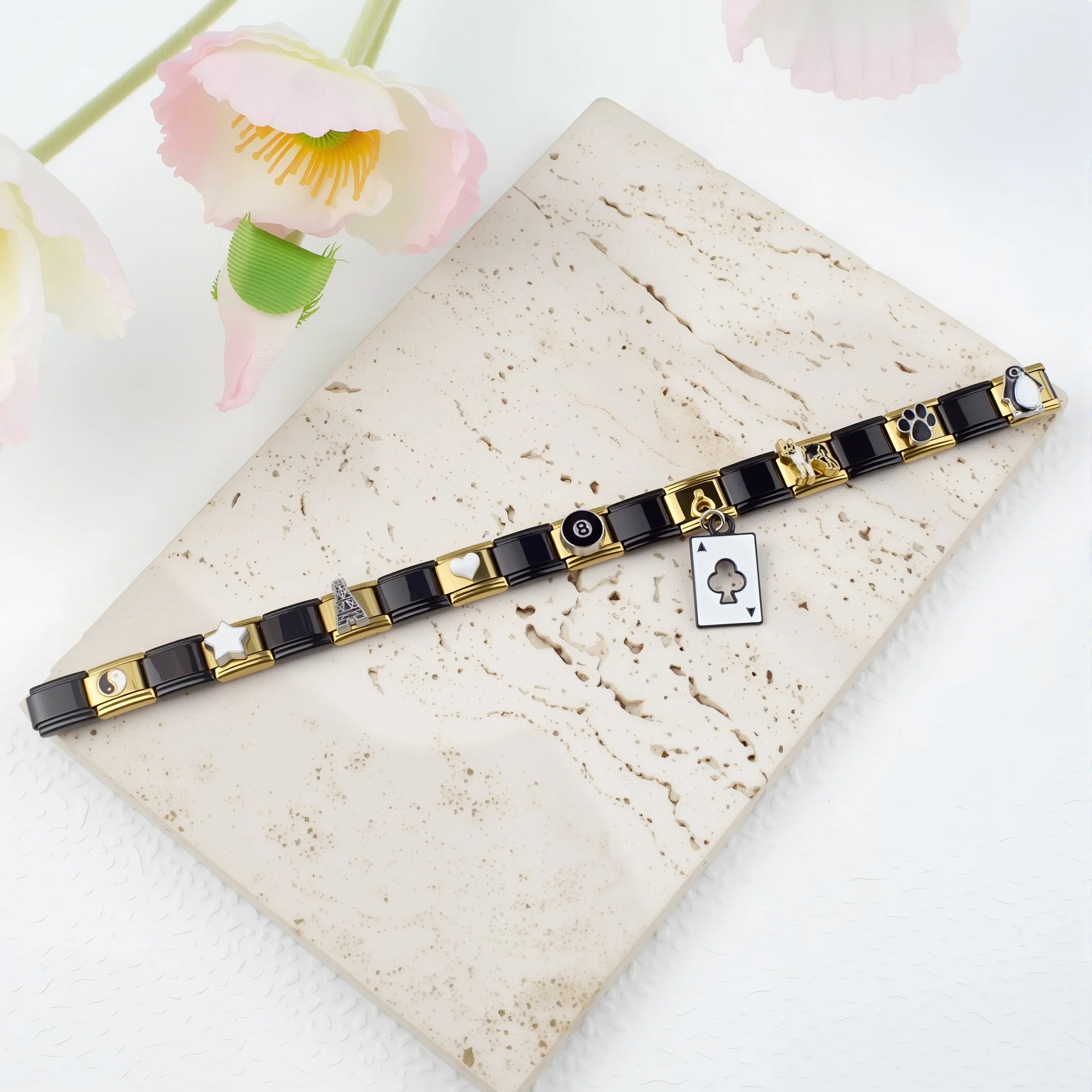 Black-and-gold modular bracelet arranged diagonally on a cream stone display